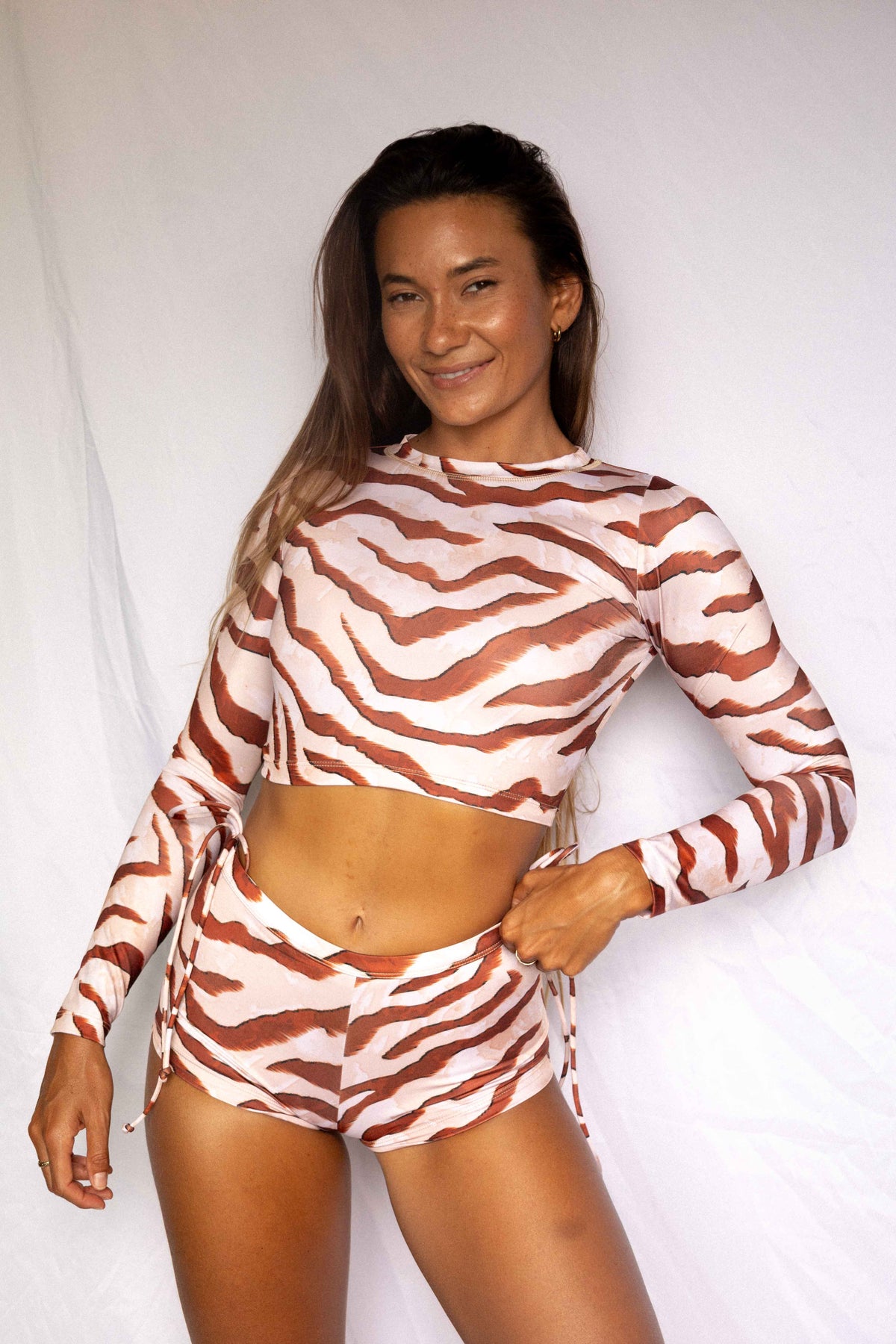 Lola Low-Rise Surf Shorts in Dune animal print, front smiling view worn with matching Lola rashguard, women's surf set by Antidote The Label