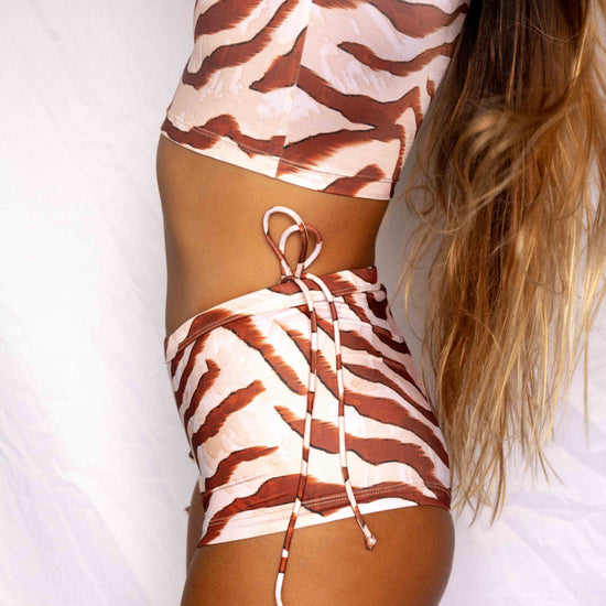 Lola Low-Rise Surf Shorts in Dune animal print, close-up side view showing side-tie detail and secure fit