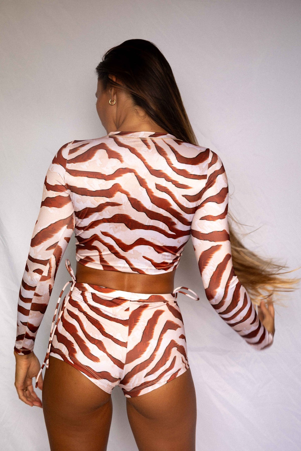 Lola Long-Sleeve Surf Rashguard in Dune animal print, back view worn with matching high-waist bottoms, women's surf rashguard set