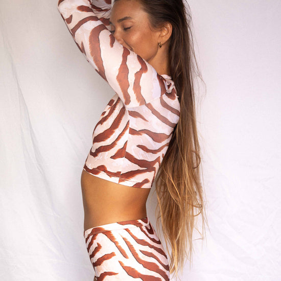 Lola Low-Rise Surf Shorts in Dune animal print, side profile view worn with matching rashguard showing streamlined silhouette