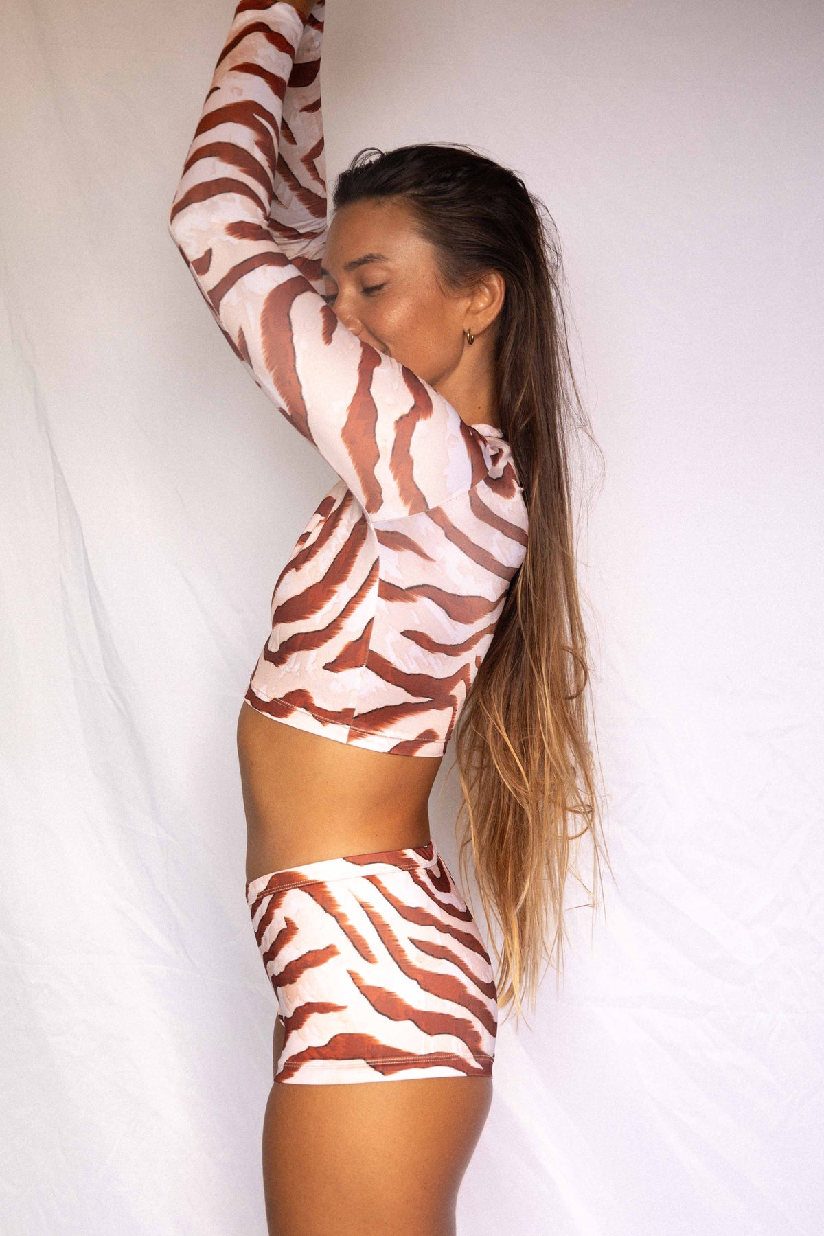 Lola Low-Rise Surf Shorts in Dune animal print, side profile view worn with matching rashguard showing streamlined silhouette