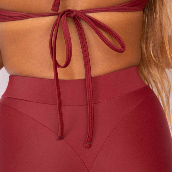 Niki Surf Shorts in Deep Merlot, close-up back detail showing V-seam waistband construction and lower back tie of matching surf top