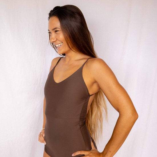 Emi Surf Suit in Coffee — front view, model smiling in earth-tone one-piece swimsuit with thin straps, Antidote The Label