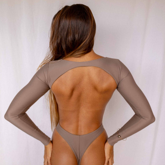 Nia Long-Sleeve Surf Suit in Taupe, full back view showing open back cutout design, long sleeves, and high-cut bottom