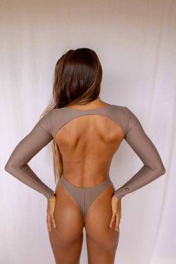 Nia Long-Sleeve Surf Suit in Taupe, full back view showing open back cutout design, long sleeves, and high-cut bottom