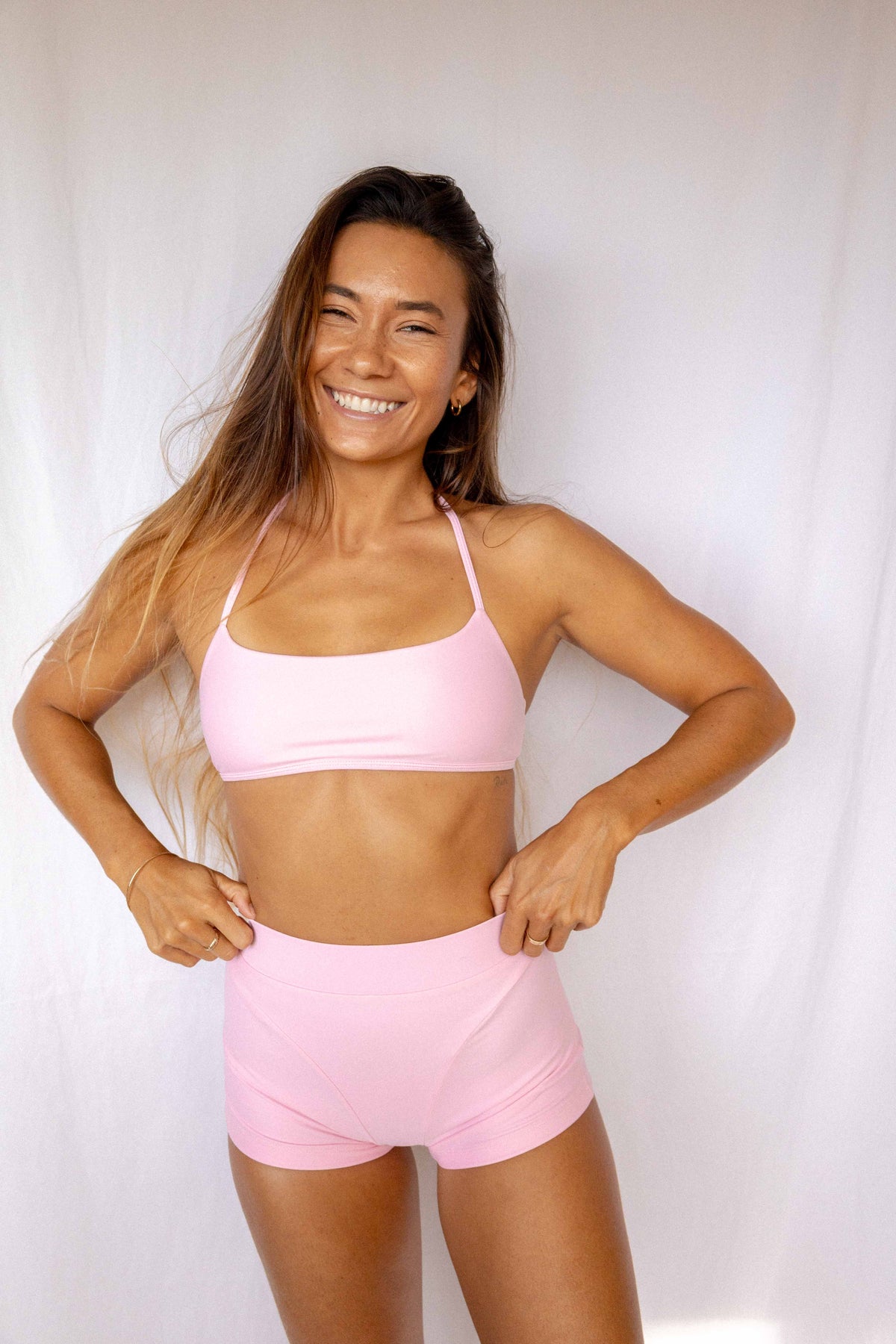 Niki Surf Top and Shorts set in Blush, smiling full front view showing halter neckline, cropped top, and high-waist short silhouette by Antidote The Label