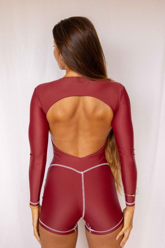 Anou Long-Sleeve Surf Suit in Deep Merlot, full back view showing open back cutout, long sleeves, and contrast stitch short construction