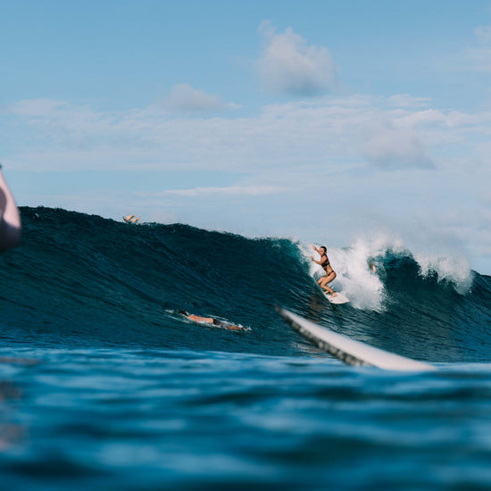 Ona Surf Top and bottoms in Deep Merlot worn surfing in ocean waves with tropical backdrop, women's performance surf top by Antidote The Label